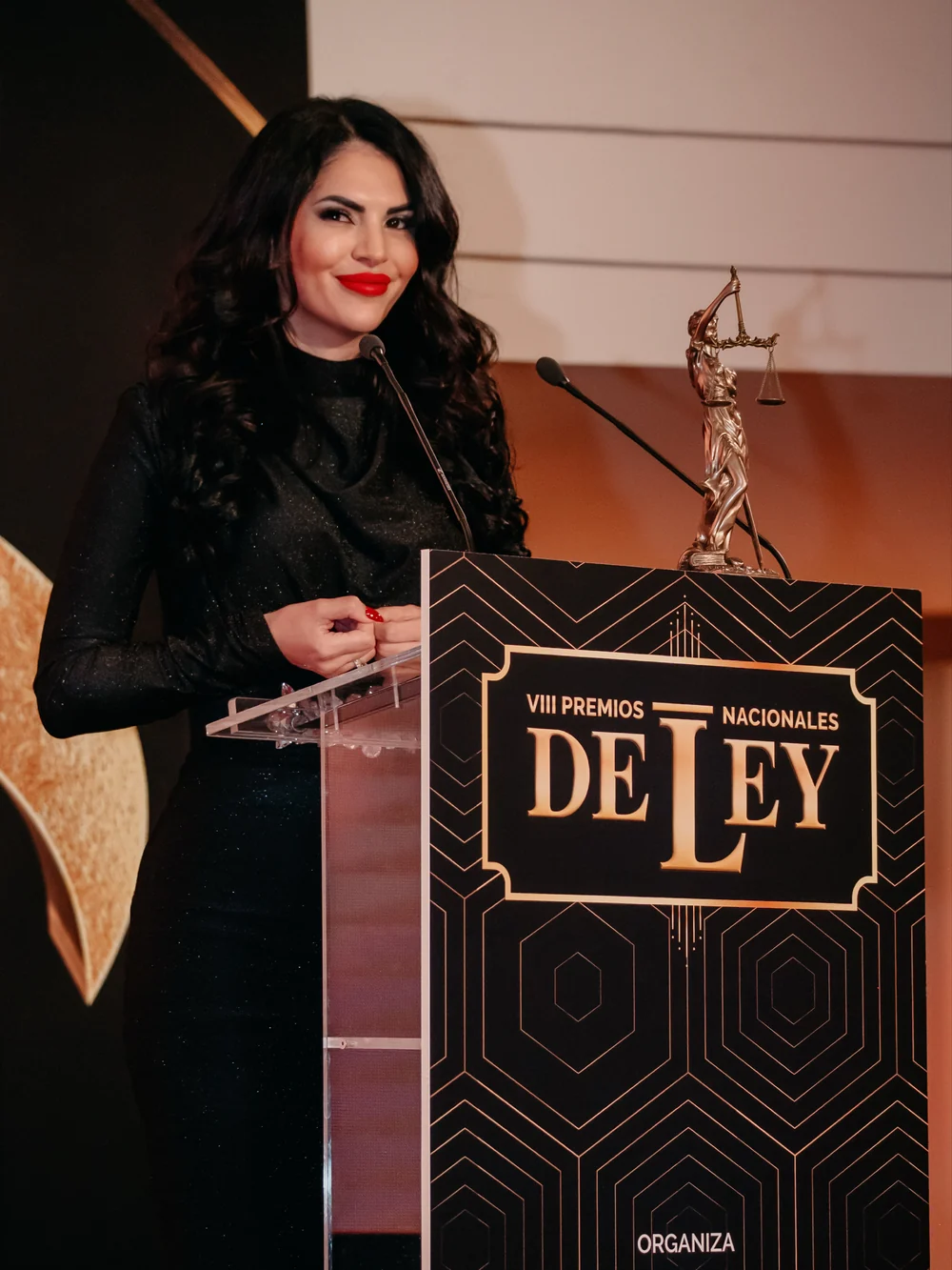 María Isabel Miranda en el atril de los Premios Nacionales De Ley, junto a la estatua de la justicia